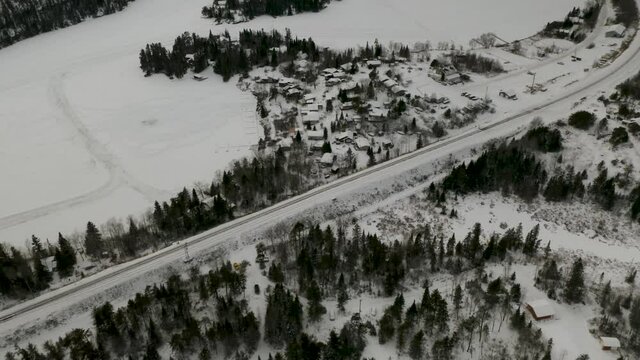 Aerial view of small northern community.  Rail way travels along side settlement as frozen lake with ice roads sit on the opposite side. Ingolf, Ontario