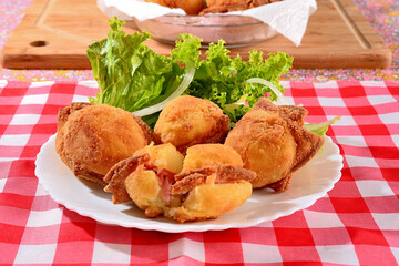 Batatas empanadas recheias de mortadela servidas com salada num prato