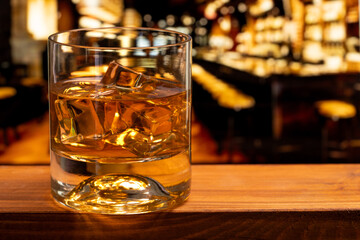 Glass of whiskey with ice cubes at a night club