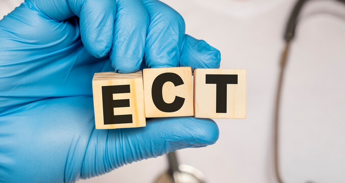 ECT Electroconclusive therapy - word from wooden blocks with letters holding by a doctor's hands in medical protective gloves. Medical concept.