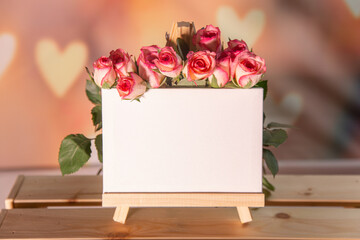 Pink roses on a wooden background, white place for text, easel, pink background for the holiday of February 14 or March 8