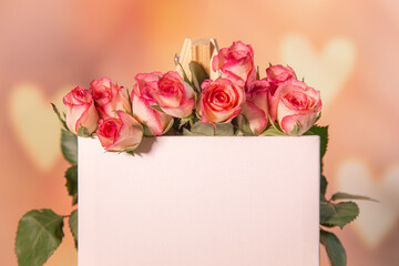 Pink roses on a wooden background, white place for text, easel, pink background for the holiday of February 14 or March 8