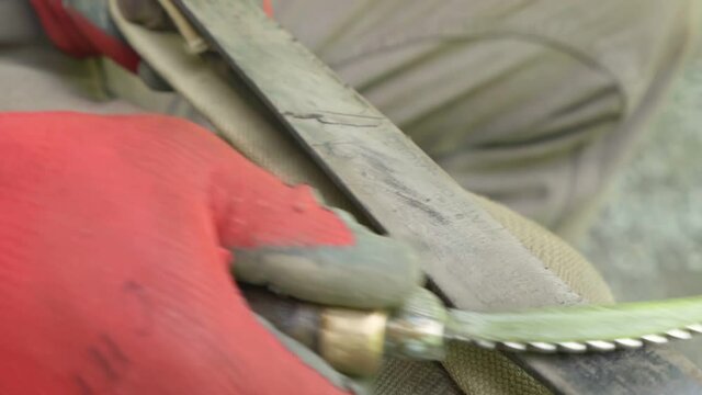whetting a serrated curved knife with an old sharpening belt - Close up