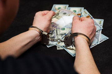 Man in handcuffs with money and drugs on dark background. The concept of punishment for possession, distribution and use of drugs. Concept no to drugs
