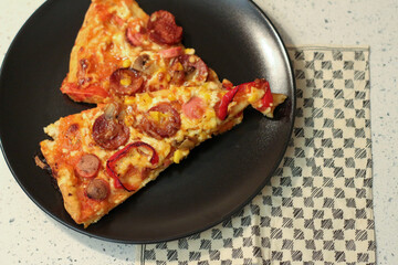 Two slices of homemade pizza served on a black plate
