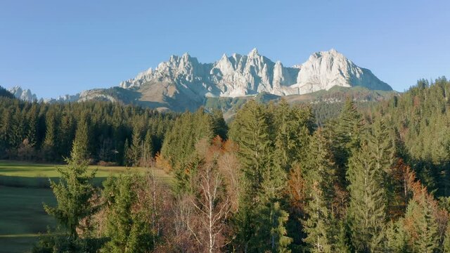 drone dolly shot over trees of mountain range of wilder kaiser in austria