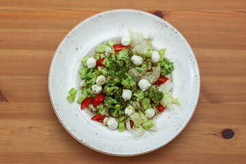 Healthy salad with vegetables on the wooden table. Tomato, lettuce , cucumber ande cheese in