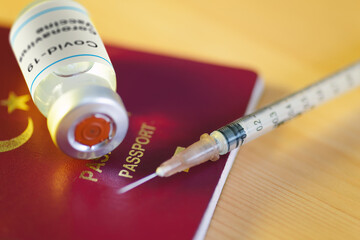 Close up shot of a coronavirus vaccine bottle with a Red colored Turkey's passport.