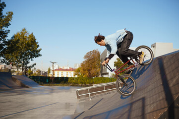 Bmx biker doing trick on ramp in skatepark
