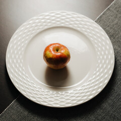 Red apple on white plate