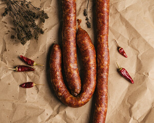 Top-down homemade dry-cured sausage with herbs and chili on brown paper