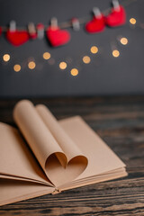 Heart made from book sheets in lights, love and valentine concept on a wooden table