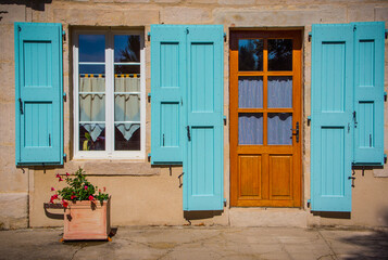 Fototapeta na wymiar Colorful shutters surround windows and doors in historic tow of Saint-Leons, France