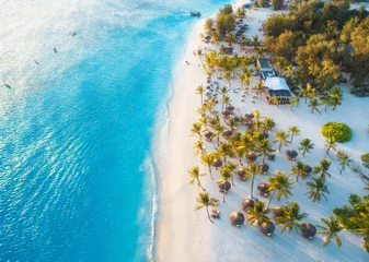 Papier Peint photo Zanzibar Vue aérienne de parasols, palmiers verts sur la plage de sable au coucher du soleil. Vacances d& 39 été à Zanzibar, Afrique. Paysage tropical avec palmiers, parasols, sable blanc, eau bleue, vagues, gens. Vue de dessus