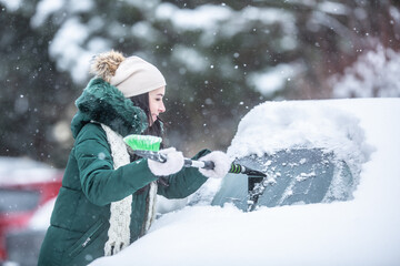 Scraping ice off the car after heavy snowfall covered it parked outdoors