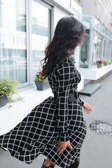 Young elegant girl posing at city street. Pretty beautiful business woman in elegant dress against city background.