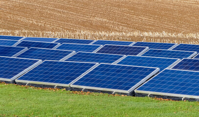 An array of photovoltaic solar panels in agriccultural setting, providing green energy. Located on a grassed field, with harrowed stubble field background. Landscape image with space for text. UK. - 406516556