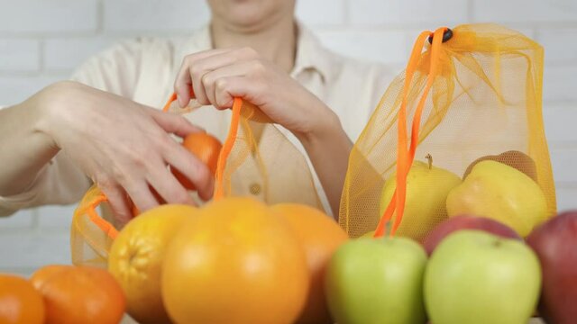 Puts fruits in an eco shopper. Woman puts fruits in reusable bags in the store.