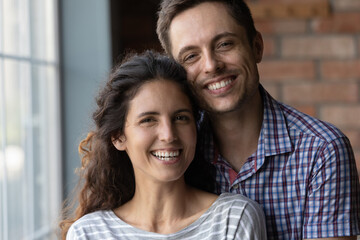 Close up portrait of happy millennial couple renters or tenants pose in new home moving together. Smiling young Caucasian man and woman celebrate relocation to own house, relax on weekend.