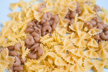 Variety of types and shapes of dry Italian pasta on blue background. Cooking concept