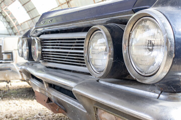 A headlight of a retro old car close up in a junk yard, recycling fee concept