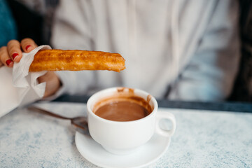 A person dipping a Churro in hot chocolate