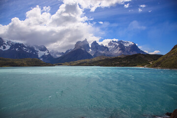 Torres del Paine vista surrounded by white fluffy clouds and blue sky. 