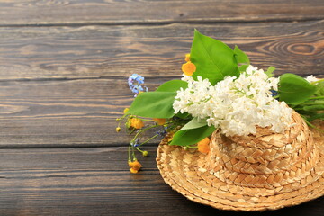 Fototapeta premium bouquet of spring flowers in a straw hat on a wooden background