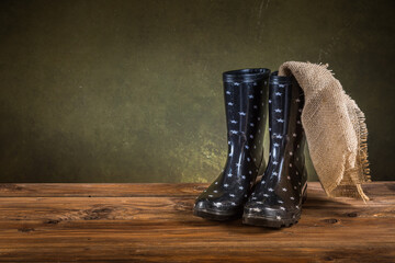 Gardening concept - gumboots with burlap on wooden background