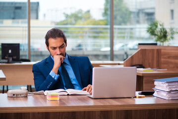 Young male employee reading book in the office