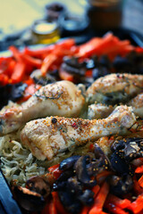 Selective focus. Baking tray with baked chicken parts, carrots and mushrooms. Korean chicken with vegetables.