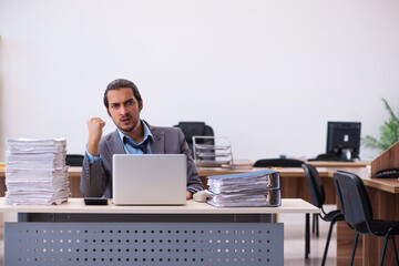 Young male employee unhappy with excessive work in the office