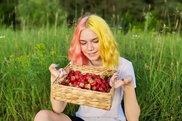 Young teenage girl with basket of fresh plucked strawberries