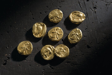 Top view of ancient gold pieces on black surface