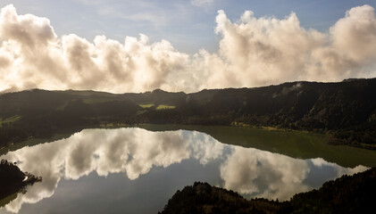 Furnas lake with reflection of trees and clouds in water. Sao Miguel island, Azores.
