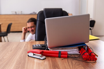 Young male employee with dynamite in the office