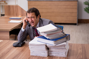 Young male employee unhappy with excessive work in the office