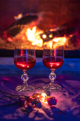 two glasses with red wine, near the fireplace, evening, blurred background