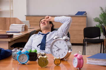 Young male employee sleeping in the office in time management co