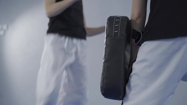 Female Martial Arts Fighter Practicing With Trainer, Punching Taekwondo Kick Pad Exercise Kicking. Training Of Kickboxer Woman Strikes With Bare Foot Mitts Punching Bag Kicking Shield