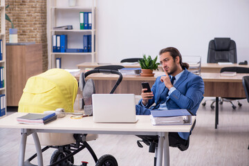 Young male employee looking after new born at workplace