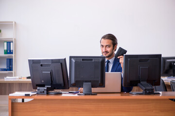 Young male employee in multitasking concept