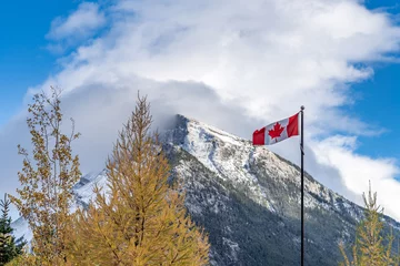 Afwasbaar Fotobehang Canada National Flag of Canada with Mount Rundle mountain range in a snowy sunny day. Banff National Park, Canadian Rockies.