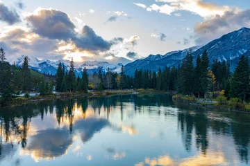 Photo sur Plexiglas Forêt dans le brouillard Bow River riverbank in autumn season sunset time. Beautiful fiery clouds reflect on water surface like a mirror. Beautiful nature scenery in Banff National Park, Canadian Rockies.