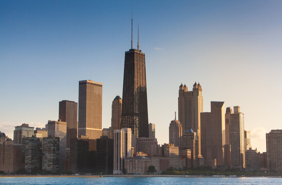 Chicago Illinois city sunset skyline and cityscape from Lake Michigan with John Hancock Building in the center. Evening light in the summer from sailboat at the playpen. 