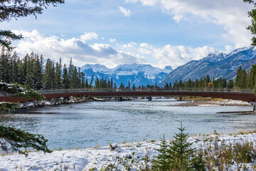 Banff Pedestrian Bridge and Bow River trail in snowy autumn day. Banff National Park, Canadian Rockies.