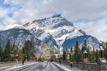 Banff Avenue in snowy autumn sunny day. Snow-covered Cascade Mountain with blue sky and white clouds in the background. Banff National Park, Canadian Rockies. Banff, Canada