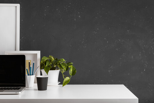 Table with laptop, office supplies, plant and space for mockup. Home office desk.