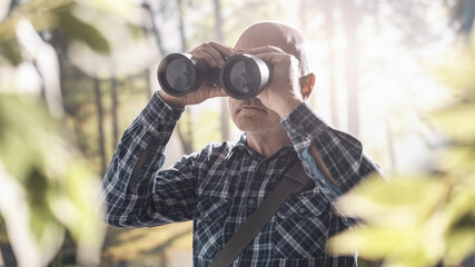 Tourist walking in a forest and using binoculars