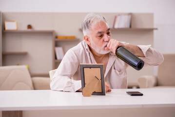 Old widower drinking alcohol at home